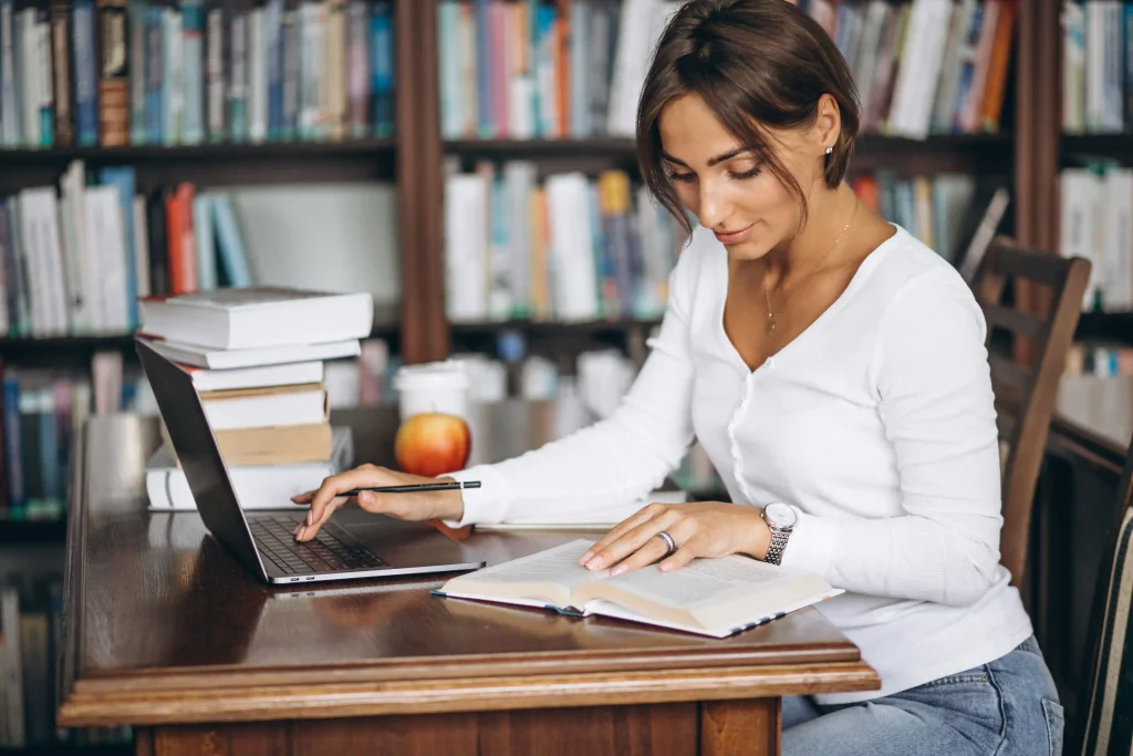 young woman sitting library using books computer copiar